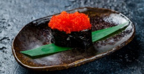 Gunkan with masago caviar on a dark stone table 