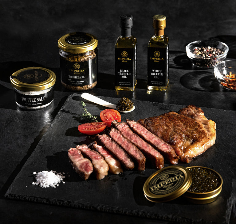 Sliced A5 Wagyu steak on slate with Imperia caviar, truffle salt, truffle sauce, black and white truffle oils, and peppercorns.