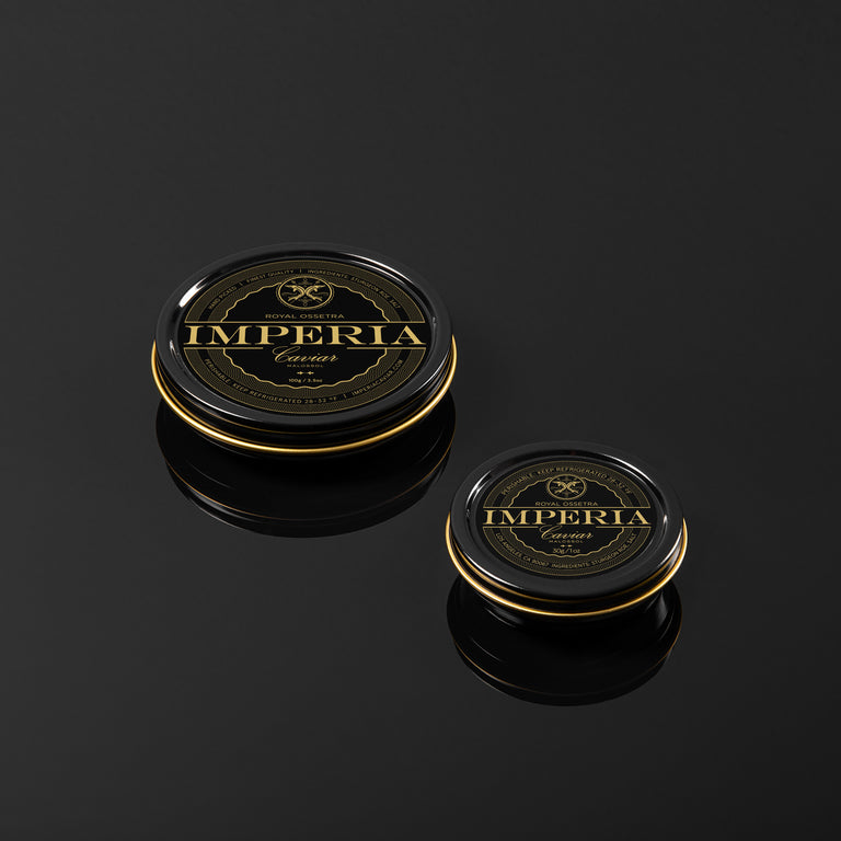Imperia Royal Ossetra Caviar 100g and 30g tins side by side on a dark reflective surface.