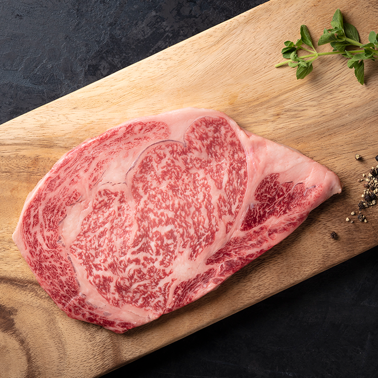 A5 Kagoshima Farms Wagyu Steak on a wooden cutting board with a sprig of parsley next to it.